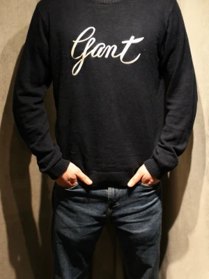 Marinblå tröja  från Gant - Snygg marinblå tröja från Gant med stor vit broderad logga på bröstet. Klassisk rund halsringning och ribbade muddar vid ärmslut och nederkant. Perfekt till jeans för en avslappnad men stilren look. Modellen är 182 cm