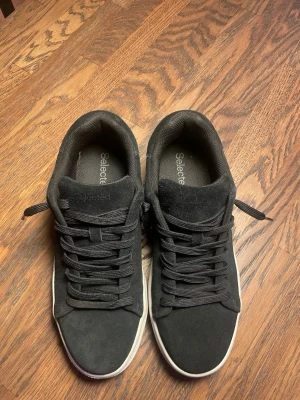 Svarta Select Mocka Sneakers - Jag är öppen till alla bud skriv ditt bud så kan vi deala fram något. Inköpta för 1200kr. Snygga svarta sneakers från Selected  med ovandel i mocka och klassisk låg profil. Skorna har svarta skosnören och vit sula som ger en clean kontrast. Perfekta för dig som gillar stilrena och tidlösa sneakers till vardagslooken. Använda bara ett fåtal gånger, tveka inte på att höra av dig. 