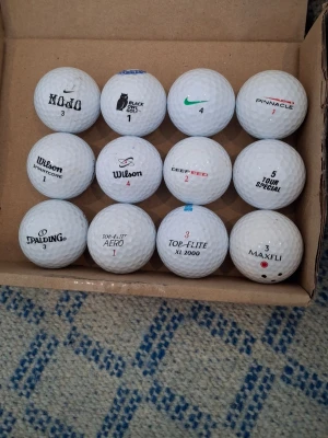 Ett Dussin Floridagolfbollar 1 - Säljer ett gäng blandade vita golfbollar från olika märken som Wilson, Nike, Pinnacle, Spalding, Maxfli och fler. Perfekt för dig som vill fylla på golfbagen med olika modeller. Alla bollar är vita och har klassisk rund form med dimple-mönster.