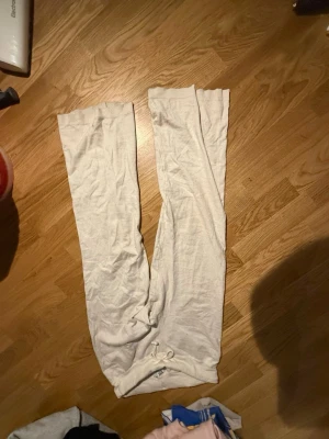 Beige leggings i mjukt material - Säljer ett par beige leggings i mjukt och stretchigt tyg. De har en enkel design utan synliga detaljer och bred resår i midjan för extra komfort. Perfekta för en avslappnad och stilren look.