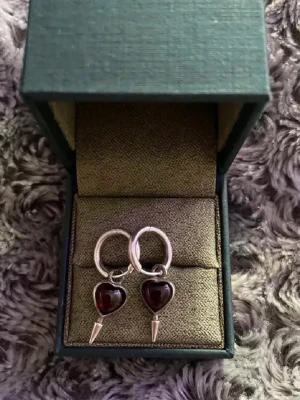 Maria Nilsdotter örhängen - Så fina silvriga örhängen ”single love earring” Med mörkröda hjärtan. Bra skick. Nypris är runt 2800/ styck men jag säljer som ett par! Man får med boxen