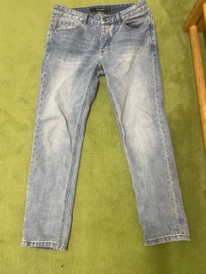 Ljusblå raka jeans - Säljer ett par ljusblå jeans med rak passform och klassisk femficksdesign. Jeansen har en snygg tvättad look och är tillverkade i denim. Perfekta för dig som gillar en avslappnad stil.