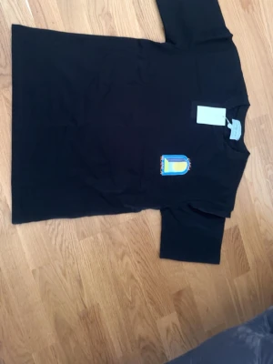 Casa Blanca svart t-shirt med tryck - Svart t-shirt från Casa Blanca med stort färgglatt grafiskt tryck på ryggen och mindre tryck på bröstet. Klassisk passform med rund hals och korta ärmar. Perfekt för dig som vill sticka ut med en cool design.