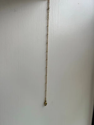 Tunt guldarmband med små pärlor - Snyggt och minimalistiskt armband i guldton med små pärlor längs kedjan. Perfekt för dig som gillar diskreta och stilrena accessoarer. Justerbar längd med enkel kedja och lås. Passar till alla outfits och är lätt att matcha med andra smycken.