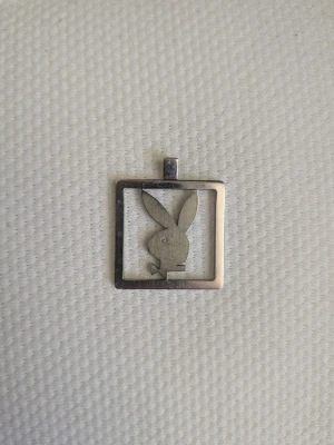Playboy kaninberlock i metall - Fyrkantig berlock i silverfärgad metall med det klassiska Playboy-kaninhuvudet i mitten. Perfekt som smyckesdetalj eller dekoration. Enkel och stilren design med tydliga former.