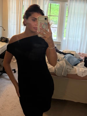 Svart offshoulder klänning - Säljer en svart, tight offshoulder klänning med kort längd. Klänningen har en stilren och enkel design som framhäver axlarna. Perfekt för dig som gillar minimalistisk stil och vill ha en klänning som känns både trendig och klassisk.