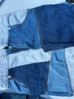 Patchwork jeanskjol i olika blå nyanser - Snygg patchwork jeanskjol i olika blå nyanser med kontrasterande denimlappar. Kjolen har fickor fram och bak, knapp och dragkedja framtill. Perfekt för dig som gillar en unik och trendig stil.