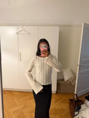 Beige  kabelstickad tröja med vida ärmar - Säljer en vit kabelstickad tröja med rund hals och extra vida ärmar. Tröjan har en croppad passform och är gjord i mjukt material, perfekt för lager på lager. Enkel men trendig design som passar till det mesta☺️
