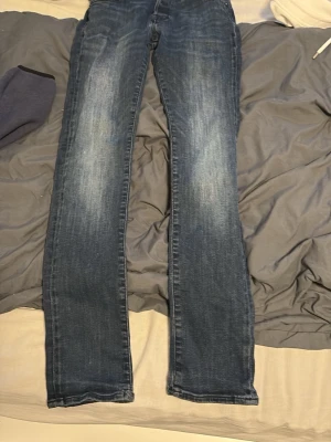 Mörkblå bootcut jeans - Snygga mörkblå  bootcut jack & jones jeans med lätt slitning framtill och klassisk femficksdesign. Jeansen har en rak passform med något utsvängda ben och är tillverkade i denim. Perfekta för en avslappnad och trendig look.