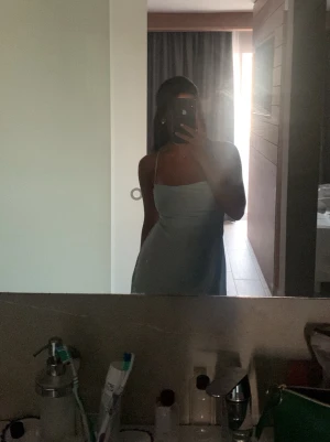 Ljusblå axelbandslös kortklänning - Säljer en ljusblå kort klänning med tunna axelband och öppen rygg med knyt. 