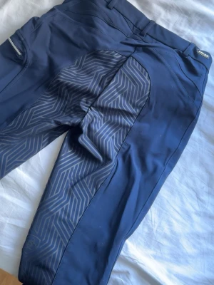 Mörkblå ridbyxor från Ariat - Säljer ett par mörkblå ridbyxor från Ariat. De har en ficka med dragkedja på låret. Säljes då de inte passag mig. Använda max 5 gånger. Nypris 1600kr