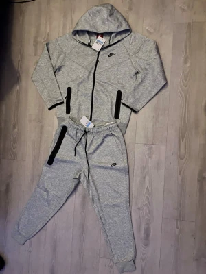 Nike Tech – Grå (M) - 🔥 Nike Tech Fleece – Grå (M) Populärt Nike Tech-set i stilren grå färg — hoodie + byxor. Mjukt material och ikonisk Tech-silhuett som sitter snyggt både till vardag och gym. I mycket fint skick! 👕✨ 💬 Pris kan diskuteras — skicka bud! 🤩  📦 Skickas ut idag!  🧵 Material: Tech fleece 🎨 Färg: grå 📏 Storlek: M 👟 Set: hoodie + byxor  #NikeTech #TechFleece #GreyFit #NikeSet #ComfyWear #StorlekM #SnabbLeverans #Streetwea
