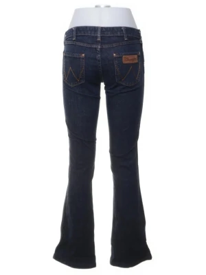 Low waist boot cut jeans  - Snygga mörkblå bootcut jeans från Wrangler med klassiska kontrastsömmar och femficksmodell. Jeansen har en låg midja och utsvängda ben, samt läderpatch med logga på bakfickan. Perfekta för en cool och avslappnad stil.
