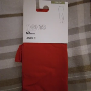 HELT NYA OANVÄNDA röda tights / strumpbyxor från Lindex, storlek 36/38.  - HELT NYA OANVÄNDA snygga röda tights från Lindex i storlek 36/38, passar troligen även någon med XS-S. De är 60 denier och tillverkade av 88% polyamid och 12% elastan, vilket gör dem både stretchiga och bekväma. Perfekta för att ge din outfit en färgklick och passar till många olika stilar och till jul. Felfria.