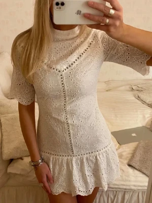 Studentklänning - Supersöt vit kort klänning med broderade spetsdetaljer och volangkant nertill. Storlek 38 men passar bättre en 36/S. Perfekt till studenten och sommaren