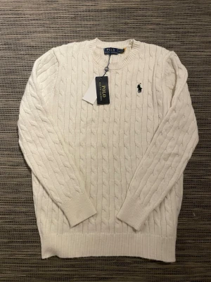 Vit kabelstickad tröja Polo Ralph Lauren - Säljer en snygg stickad tröja från Ralph Lauren! Tröjan är i mycket bra skick och har inga defekter. Är i storlek XL men passar perfekt på mig som brukar ha M ibland S. Qr-koden fungerar som den ska. Om ni har några andra frågor så är de bara att höra av er!😊