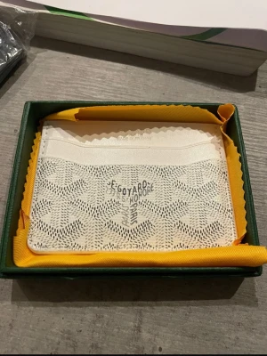 Vit kortfodral  - Säljer ett stilrent vitt kortfodral med det klassiska mönstret och loggan tryckt på framsidan. Fodralet har flera fack för kort och är tillverkat i exklusivt läder. Perfekt för dig som vill ha något både snyggt och praktiskt i fickan.