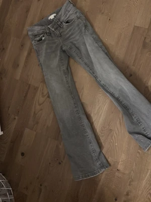 Grå bootcut jeans från Gina Tricot - Säljer ett par gråa bootcut jeans från Gina Tricot. Jeansen har klassisk femficksmodell, normal midja och utsvängda ben. Perfekta till en avslappnad och trendig look. Materialet är mjukt denim i bomull.