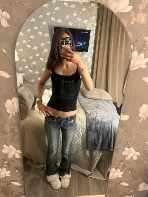 Grå bootcut jeans med vita sömmar - Säljer ett par grå bootcut jeans med tydliga vita kontrastsömmar och låg midja. Jeansen har klassiska fickor fram och bak, samt dekorativa detaljer på bakfickorna. Perfekta för en trendig och avslappnad look.