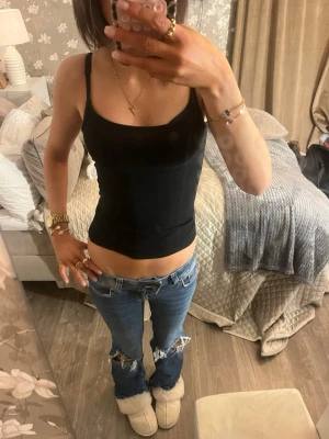 Blå slitna bootcut jeans - Säljer ett par blå bootcut jeans med slitningar och hål vid knäna. Jeansen har låg midja och klassisk femficksdesign. Perfekta för en avslappnad och trendig look. Är 171 för referens 