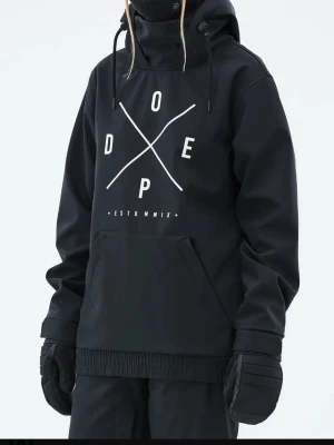 Svart vindjacka från Dope - Snygg svart vindjacka från Dope med stor vit logga och text på bröstet. Stora ventilations dragkedjor under armarna, perfekt placerade för effektiv ventilation.