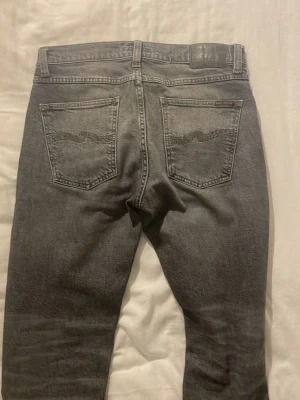 Svarta raka jeans i tvättad denim - Säljer ett par svarta jeans med rak passform och tvättad finish. Jeansen har klassisk femficksdesign och är gjorda i denim. Perfekta för dig som gillar en enkel och stilren look.