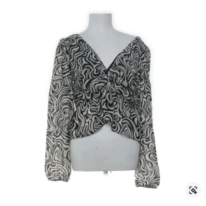 Zebramönstrad blus från H&M XS - Säljer en svartvit zebramönstrad blus från H&M i storlek XS. Blusen har långärmade, transparenta ärmar, v-ringning både fram och bak samt knytband i nacken. Materialet är lätt och luftigt, perfekt för att sticka ut med ett coolt mönster.