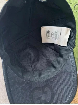 Svart keps från Gucci med GG-mönster - Snygg svart keps från Gucci med det klassiska GG-monogrammet ton-i-ton över hela kepsen. Kepsen har böjd skärm och är tillverkad i ett slitstarkt tygmaterial. Perfekt accessoar för en trendig streetstyle-look.