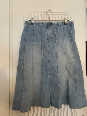 Ljusblå jeanskjol från ONLY - Säljer en ljusblå lång jeanskjol från ONLY med klassisk denimlook och vertikala sömmar. Kjolen har knapp och dragkedja framtill. 