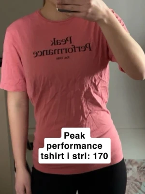 Rosa Peak Performance t-shirt - Säljer en rosa t-shirt från Peak Performance med svart tryck framtill. Klassisk rund halsringning och korta ärmar. Tillverkad i mjuk bomull som känns skön mot huden. Fint skick förutom skrynklig då den inte används men går att fixa me en tvätt eller strykning