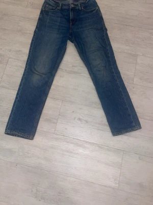 Blå raka jeans från Jack & Jones  - Klassiska blå jeans från Jack & Jones med rak passform och fem fickor. Jeansen har en vintage tvätt och tydliga sömmar. Tillverkade i slitstarkt denimtyg, perfekta för en avslappnad och tidlös stil.
