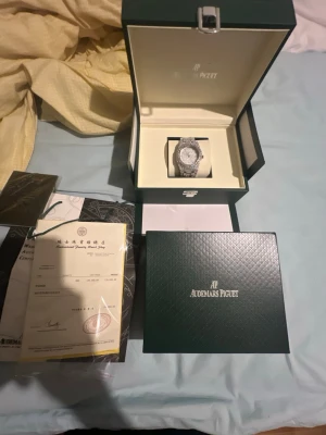 Audemars Piguet Royal Oak diamantklocka - Exklusiv Audemars Piguet Royal Oak klocka i silver med helgjuten design och täckt av gnistrande diamanter på både urtavla och armband. Klockan levereras i originalbox med certifikat och tillbehör. Perfekt för dig som vill sticka ut med lyxig stil.