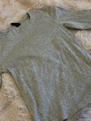 Grå kort ärmad ribbad topp - En enkel och stilren grå långärmad topp med rund halsringning. Toppen är ribbad och har en mjuk känsla, perfekt att matcha med jeans eller kjol. Passformen är normal och materialet känns bekvämt mot huden. Obs knappt använd☺️