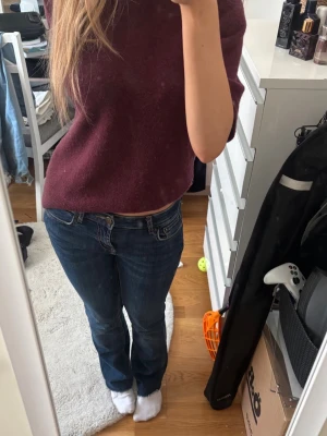 Mörkblå bootcut jeans - Säljer ett par mörkblå bootcut jeans med klassisk femficksdesign och låg midja. Jeansen har en snygg tvätt och raka ben som går ut lite nedtill för en avslappnad look. Perfekta till vardags och passar till det mesta i garderoben.