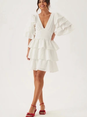 Studentklänning bubbleroom - Superfin vit klänning med v-ringning, voluminösa volangärmar och flera lager volanger i kjolen. Öppen rygg med knappdetalj och lätt struktur i tyget. Säljer då jag hittande en annan kläning och behöver inte denna💕