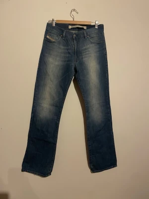 Blå raka jeans från diesel industry - Säljer ett par klassiska blå jeans från diesel industry med raka ben och fem fickor. Jeansen har en snygg tvätt med ljusare partier framtill och bakfickor med diskret söm. Perfekta till en avslappnad stil.