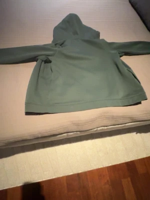 Grön zip-hoodie från Sail racing - Snygg grön hoodie från Sail Racing med dragkedja framtill och en bröstficka. Hoodien har en klassisk huva och är tillverkad i mjukt material som känns skönt mot huden. Perfekt för en avslappnad stil och enkel att matcha med jeans eller joggers.