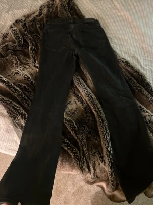 Svarta bootcut jeans - Säljer ett par svarta bootcut jeans med klassisk femficksdesign. Jeansen har utsvängda ben och normal midja. Perfekta för dig som gillar en retroinspirerad look. Materialet känns som bomullsdenim med lite stretch. 
