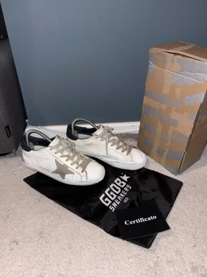 Golden Goose Superstar vita sneakers - Säljer mina golden goose skor stl 42. Skorna är i bra skick men har som de flesta golden goose skor lite slitningar på sulan. Orginalbox och dustbag medföljer. Hör av dig vid frågor och funderingar!