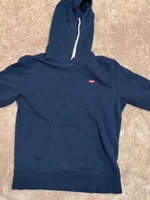 Levis hoodie - Säljer den här snygga blåa hoodien från Levis. Storlek s. Längd 67cm, bredd armhåla till armhåla 54cm, ärmlängd från armhåla neråt 52cm😁