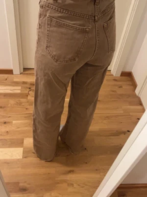 Bruna vida högmidjade jeans från lager 157 - Säljer ett par bruna jeans med raka, vida. Byxorna har hög midja och ett par fläckar vid bakfickan och på låret (se på bild)