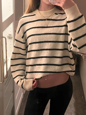 Randig stickad tröja från H&M - Säljer en krämvit stickad tröja från H&M med svarta ränder på, super skön ull material så sticks inte alls!! ❤️