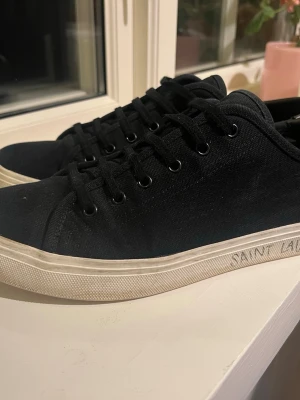 Svarta Saint Laurent canvas sneakers 100% äkta  - Svarta sneakers från Saint Laurent i canvasmaterial med vita gummisulor och svarta skosnören. Har skolåda och dustbags samt kvitto. Nypris 7000 säljer för 2299, 