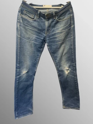 blå jeans från dressmann - Snygga blå jeans med slitningar på båda benen och klassisk femficksdesign. Jeansen har en tvättad look med ljusa partier och är tillverkade i denim. Perfekta för en avslappnad och trendig stil.