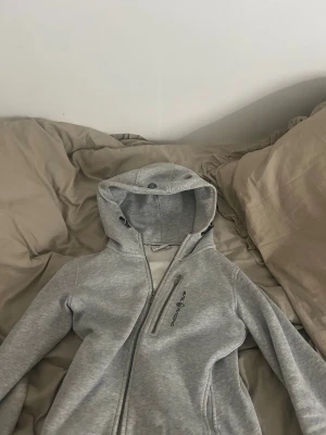 Ljusgrå zip hoodie från Sail Racing - Säljer en ljusgrå hoodie från Sail Racing med dragkedja framtill och en extra bröstficka med dragkedja. säljer på grund av att den inte kommer till användning💓 köpt här tidigare på plick om ni undrar☺️