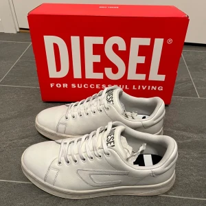 Diesel skor - Ett par stilrena vita, läder sneakers från märket Diesel. Nypris ca 2000kr, sparsamt använda, endast lite smutsiga på sulan (bild 5). Hör gärna av er vid frågor!