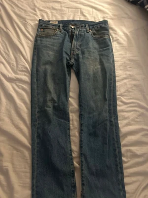 Blå raka jeans från Levi’s - Klassiska blå jeans från Levi’s med rak passform. Jeansen har en ljus tvätt och detaljer som Levi’s-lapp bak i midjan.