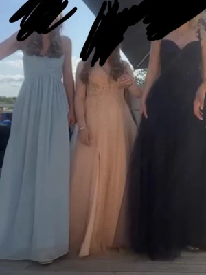 balklänning - Säljer en elegant ljusblå långklänning med draperad byst och smala axelband. Klänningen har en flytande, luftig kjol och är perfekt för student eller bal.