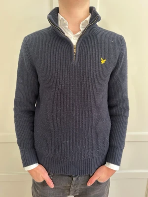 Mörkblå stickad tröja från Lyle & Scott - Mörkblå ribbstickad tröja från Lyle & Scott quarterzip  och hög krage!🔥Tröjan har det klassiska gula logomärket på bröstet och långa ärmar. Perfekt för lager på lager och ger en stilren look.🧊 Kan kombineras med skjorta och t-shirt perfekt!👌 🤩 Pris kan diskuteras😎