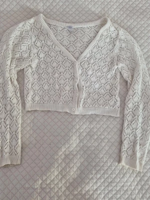 Croppad stickad kofta med mönster  - Söt croppad och mönstrad stickad kofta från Lindex💕 stl 146 men passar fint på XS, ärmlängd är även tillräcklig🫶 Perfekt över ett linne! Har lite smitsiga ärmslut, men det bör gå bort vid tvätt! 